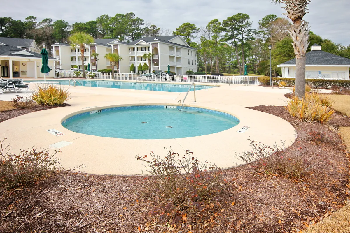 A vibrant pool area with a swimming pool, hot tub, lush surrounding greenery, and a glimpse of the residential building. The scene captures people swimming, relaxing by the pool, and socializing, all within a lively community setting.